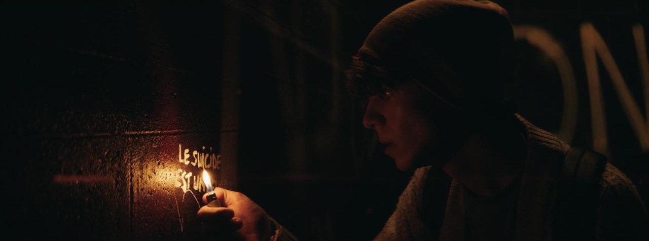 Benjamin éclaire un graffiti à la flamme d'un briquet